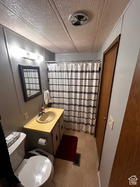 Bathroom with vanity, a shower with curtain, a textured ceiling, and toilet