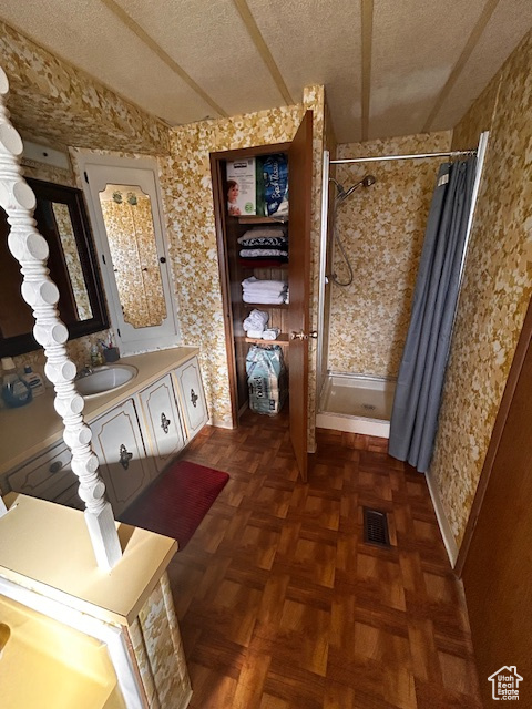 Bathroom featuring a shower with curtain, vanity, a textured ceiling, and parquet flooring