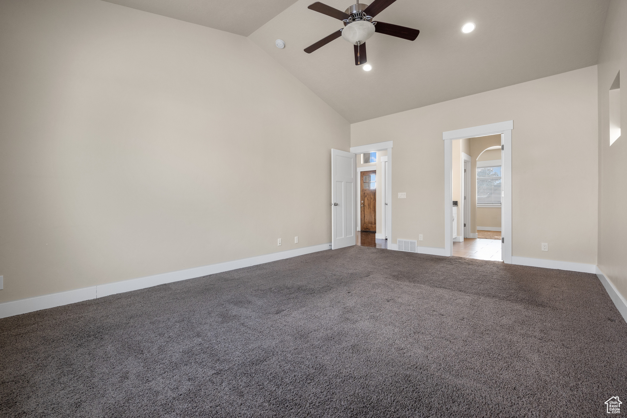 Unfurnished room with ceiling fan, carpet flooring, and high vaulted ceiling