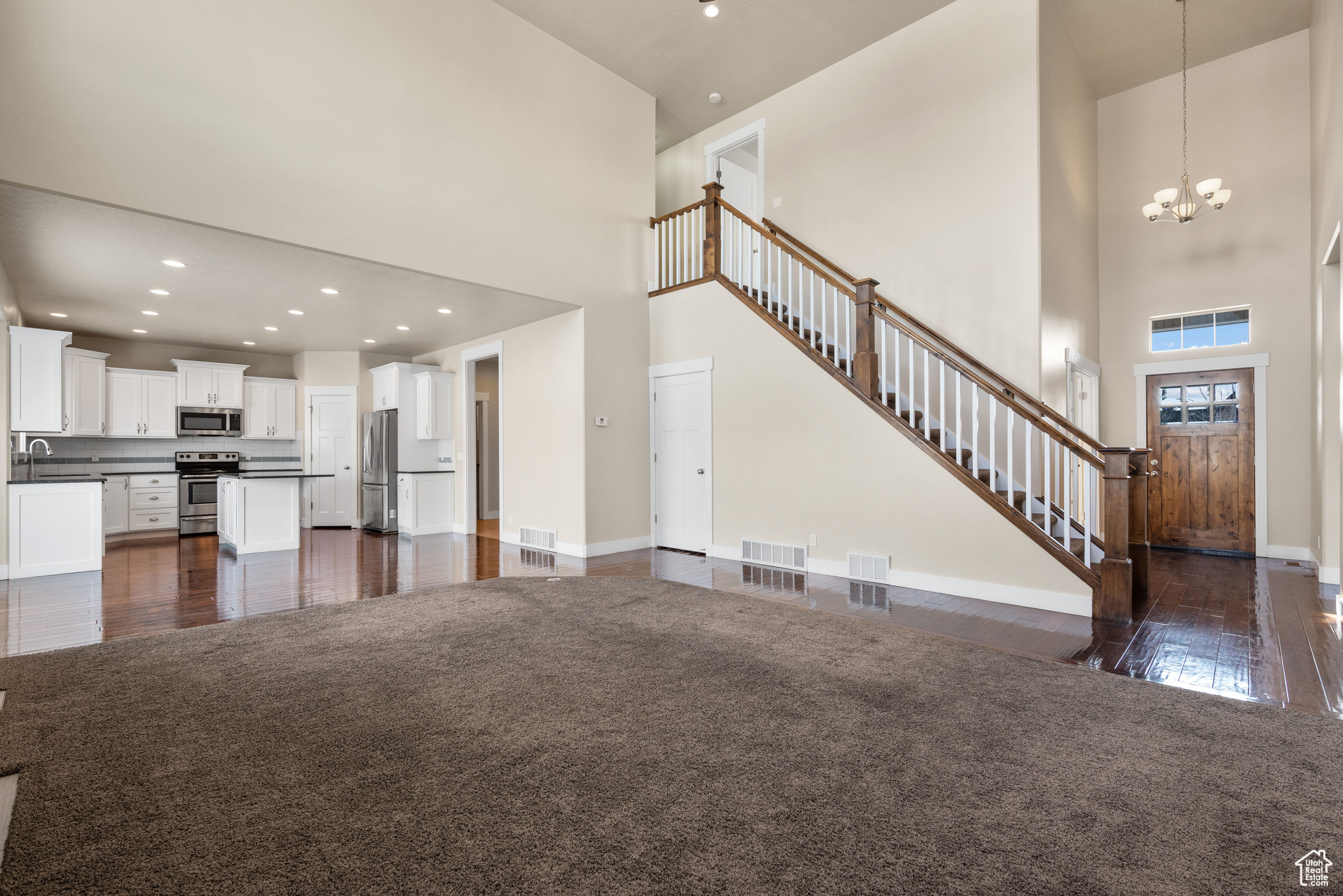 Unfurnished living room with an inviting chandelier, sink, and a high ceiling