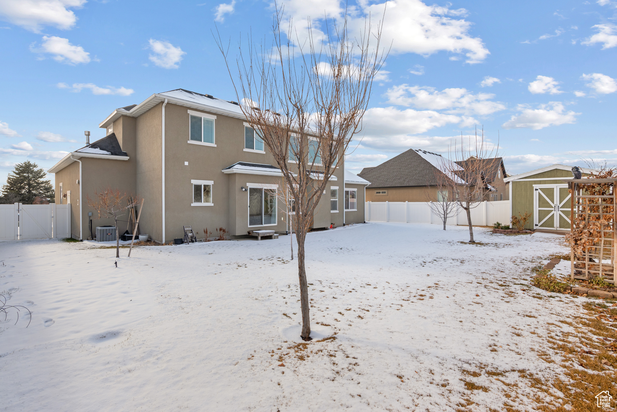 Snow covered property featuring a storage shed and central AC