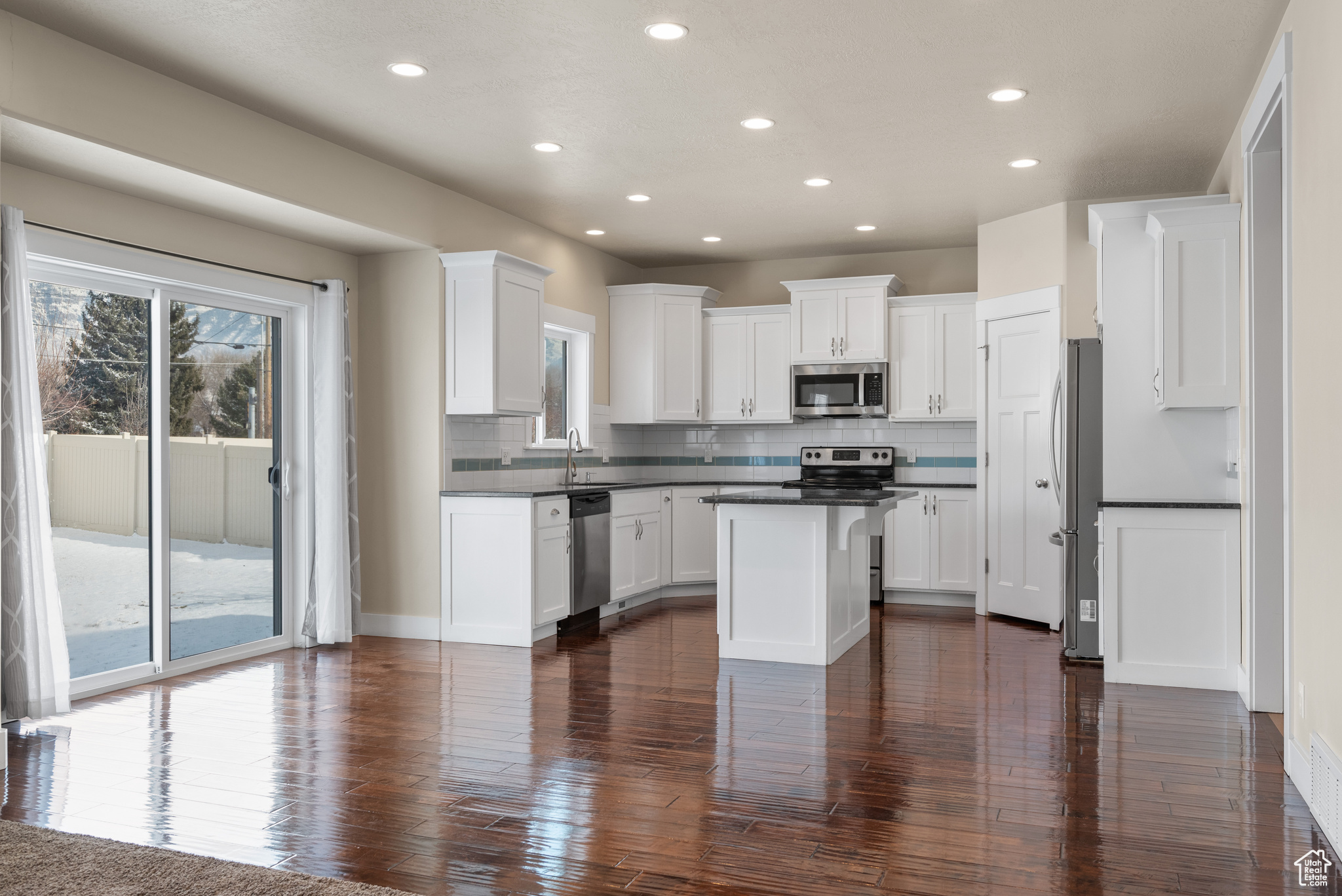 Kitchen with white cabinetry, tasteful backsplash, stainless steel appliances, and a kitchen island