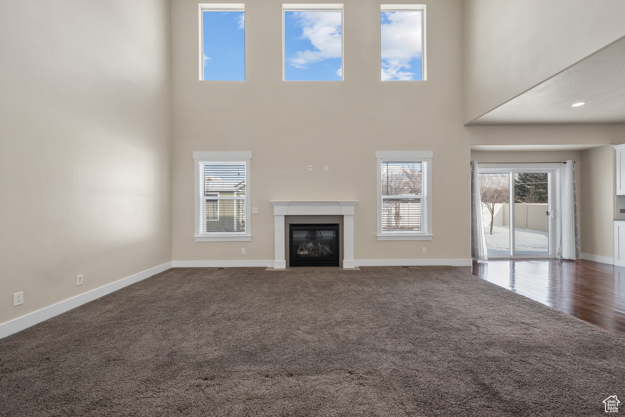 Unfurnished living room featuring dark carpet and a high ceiling