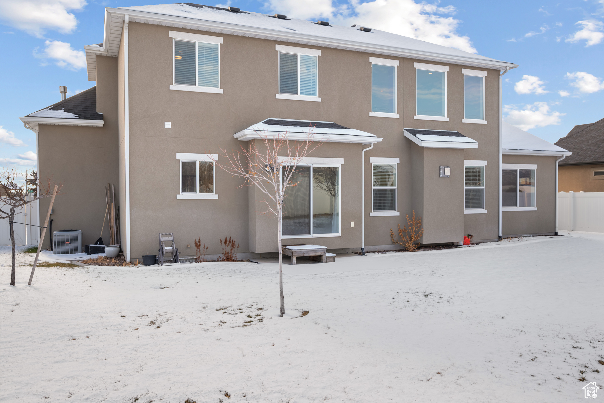 Snow covered back of property with central air condition unit