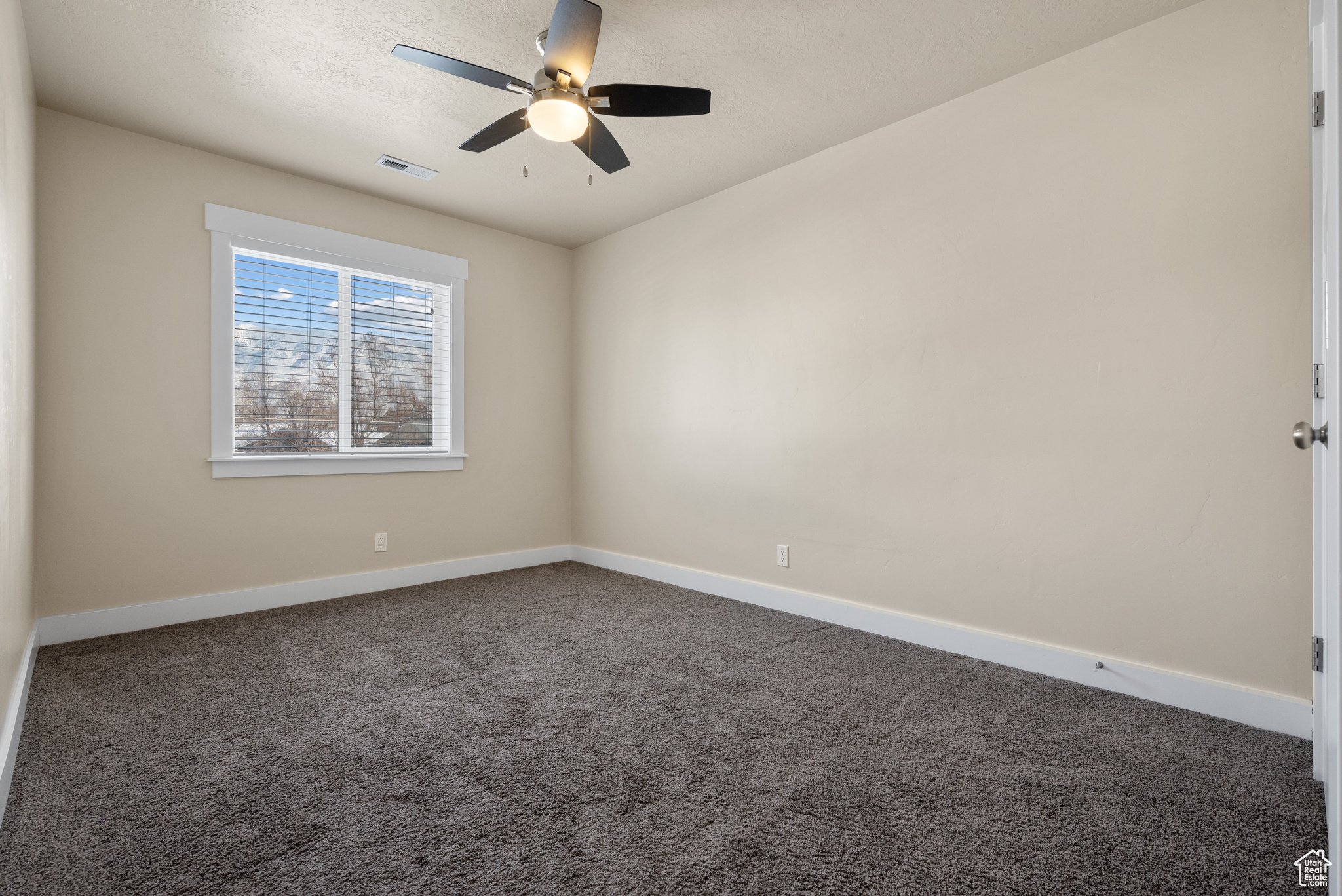 Spare room featuring ceiling fan and dark colored carpet