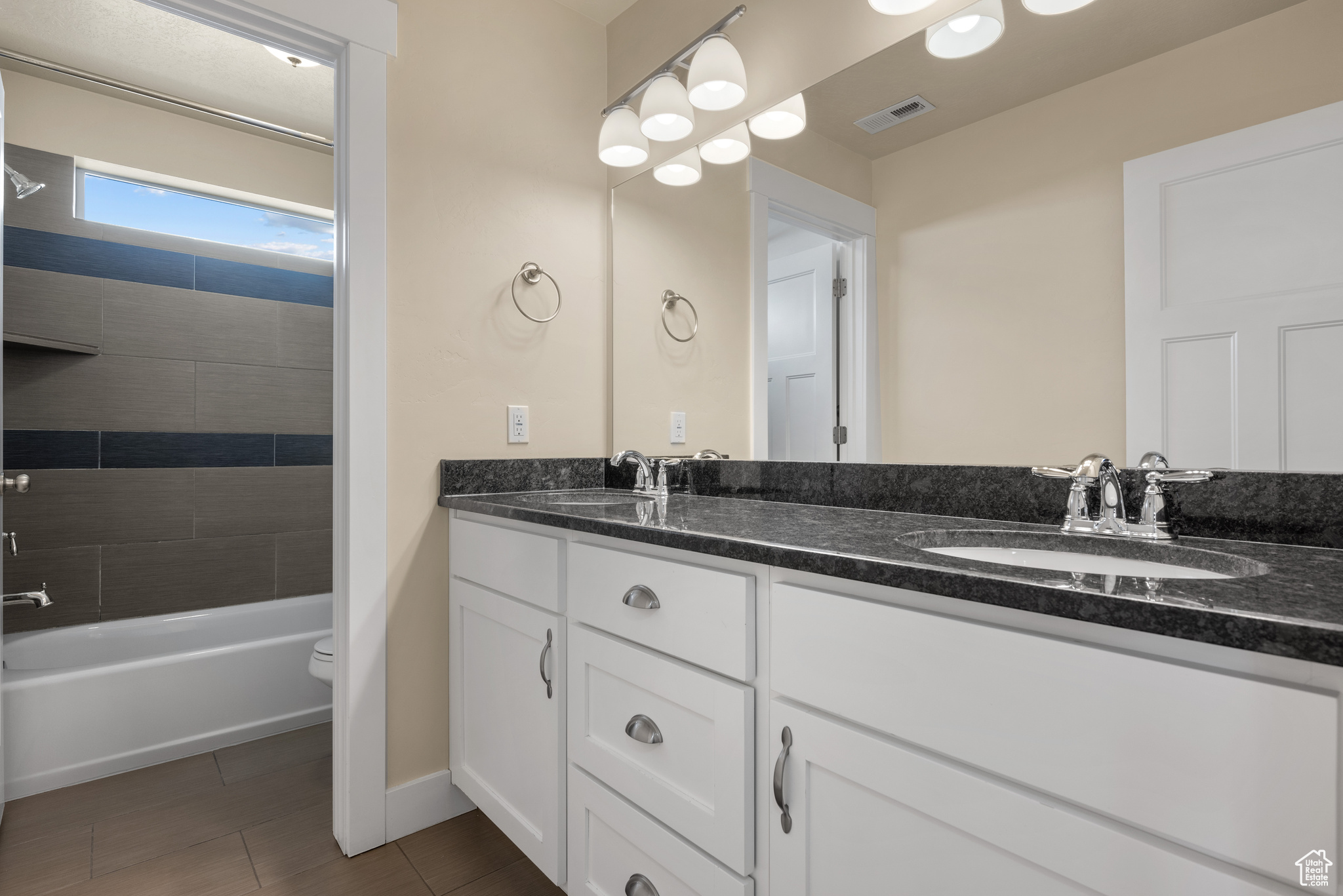 Full bathroom with vanity, toilet, and tiled shower / bath combo