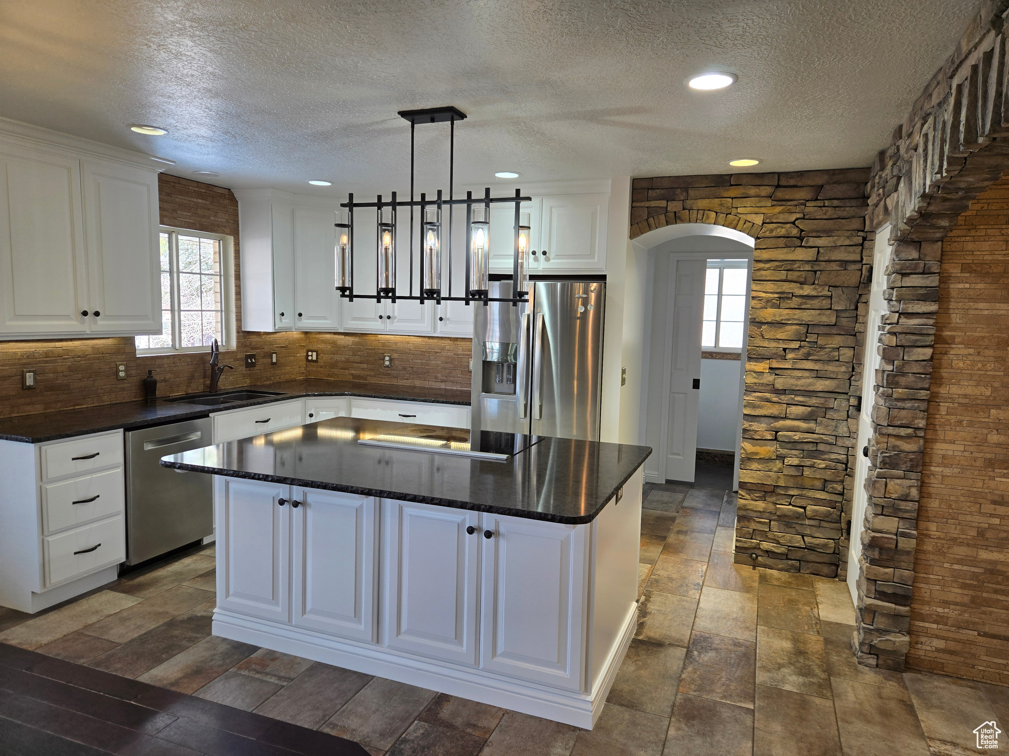 Kitchen with sink, a center island, hanging light fixtures, stainless steel appliances, and white cabinets