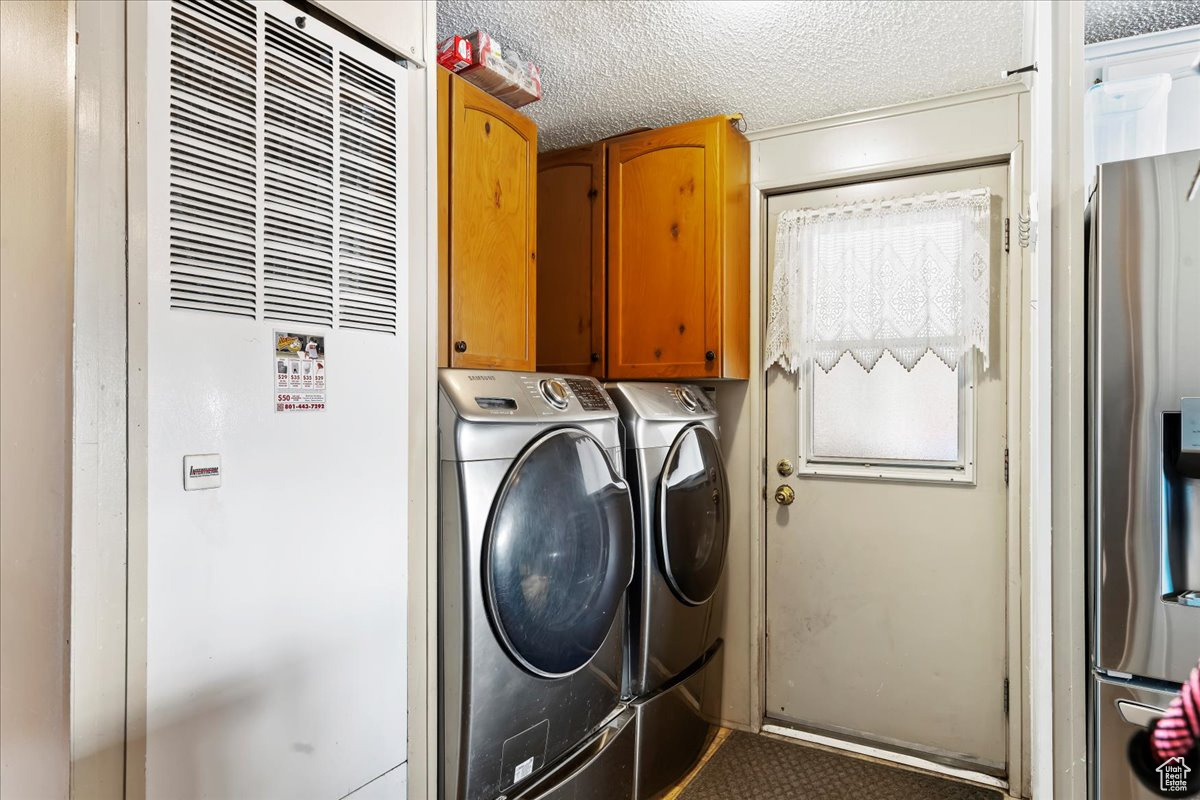 Clothes washing area featuring cabinets, a textured ceiling, and independent washer and dryer