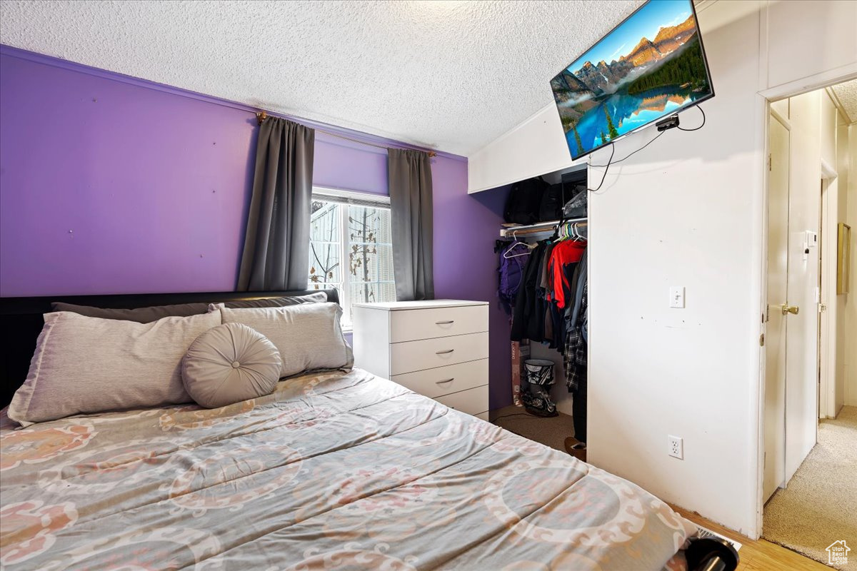 Bedroom with a textured ceiling, carpet floors, a closet, and lofted ceiling