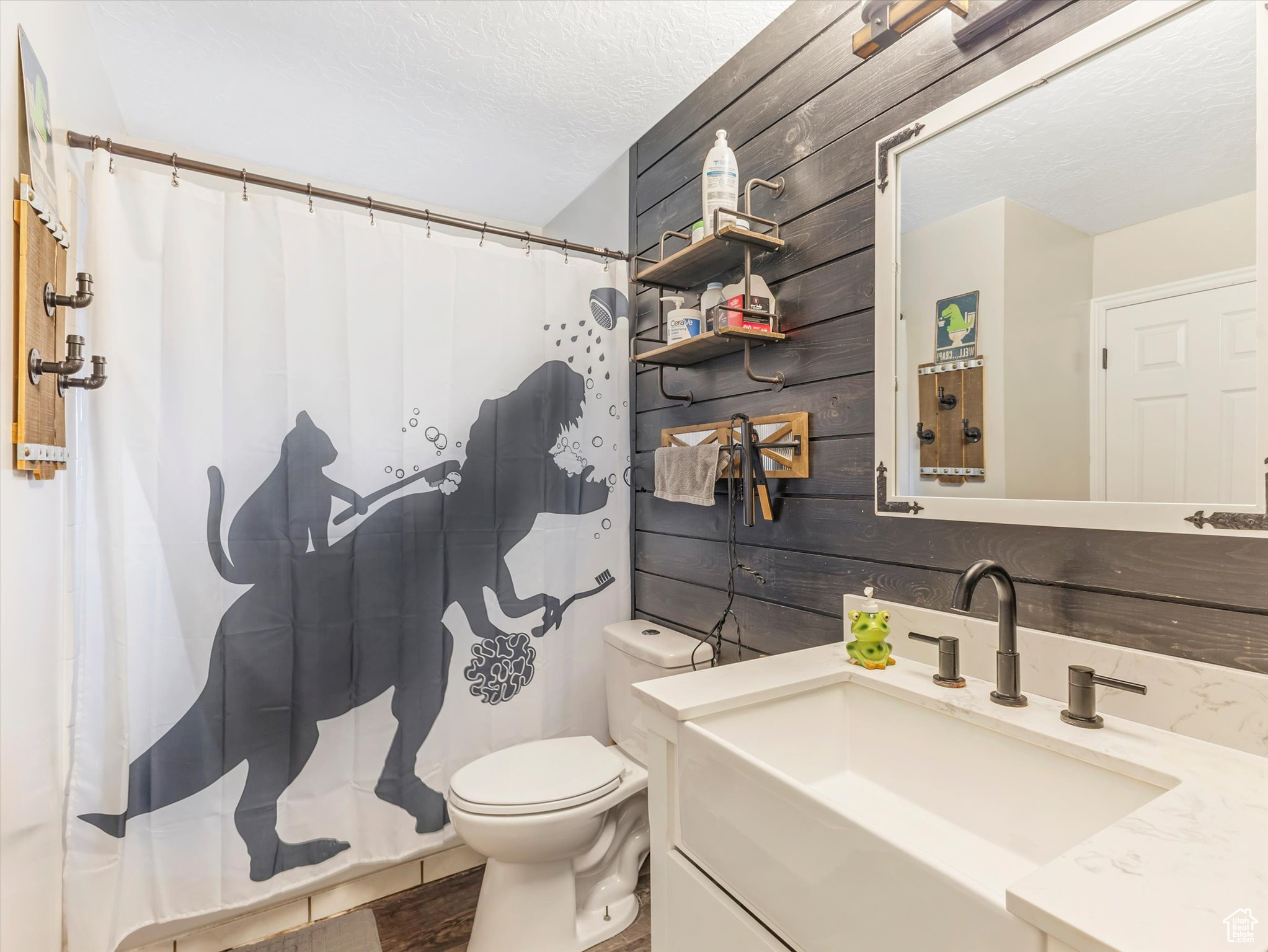 Bathroom with wood walls, hardwood / wood-style floors, a textured ceiling, toilet, and vanity