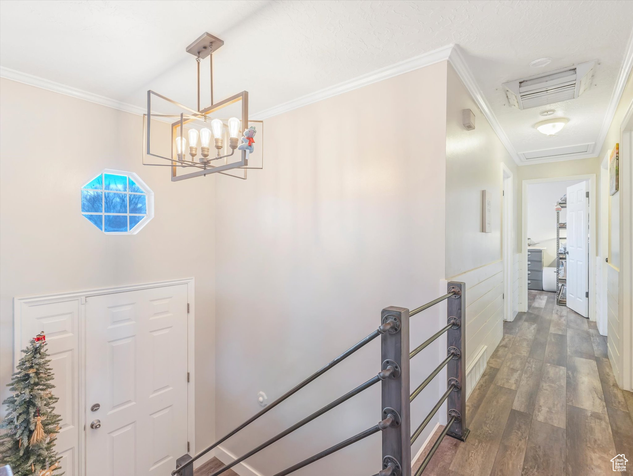 Entrance foyer featuring dark hardwood / wood-style floors, crown molding, and a chandelier