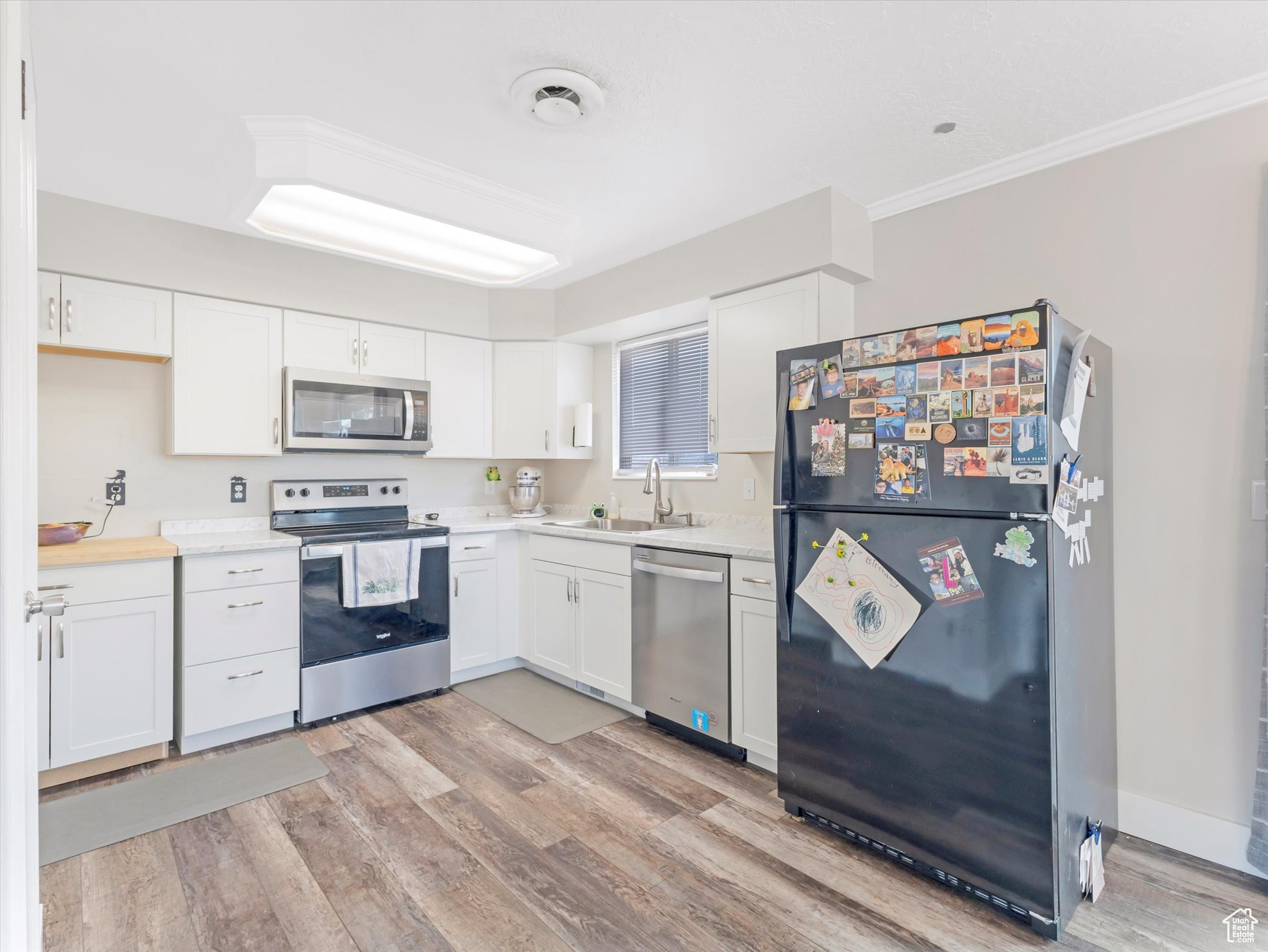 Kitchen featuring white cabinetry, sink, light hardwood / wood-style floors, and appliances with stainless steel finishes