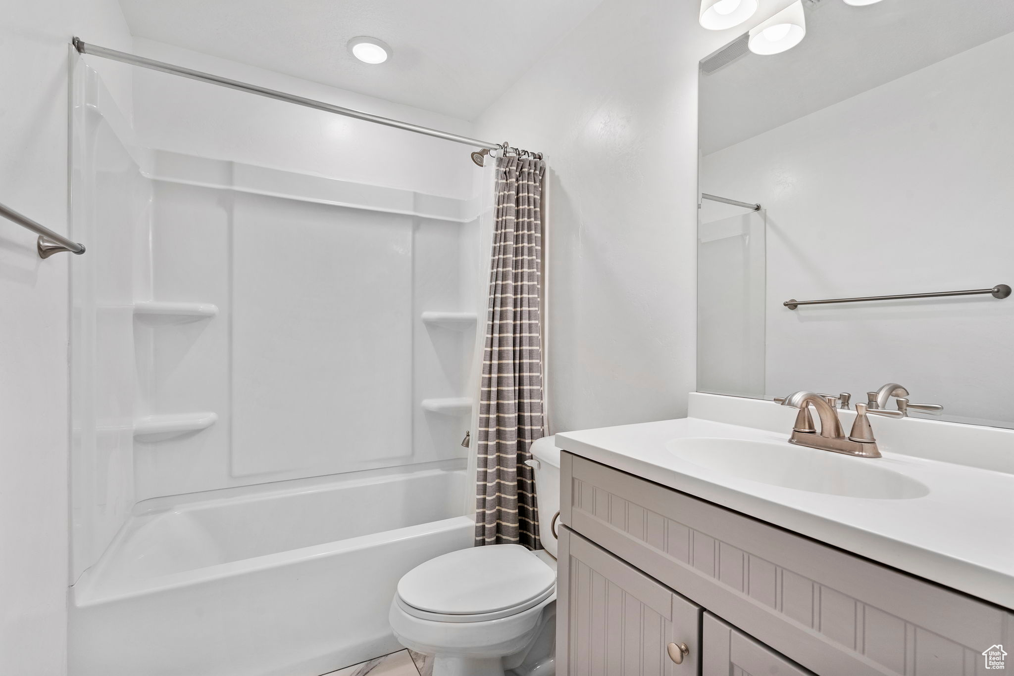 Full bathroom with vanity, shower / bath combination with curtain, and toilet