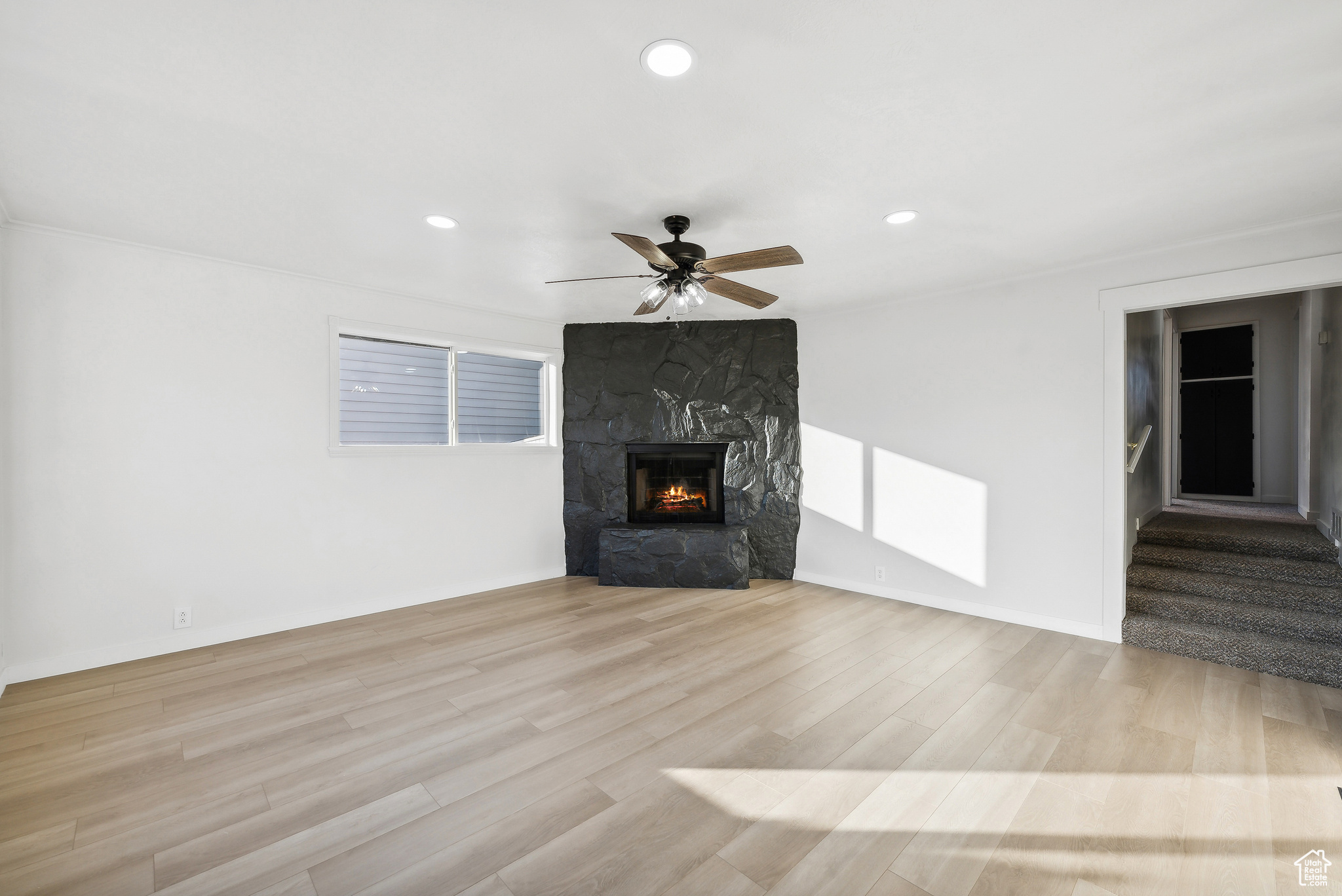 Unfurnished living room featuring a fireplace, light hardwood / wood-style flooring, and ceiling fan