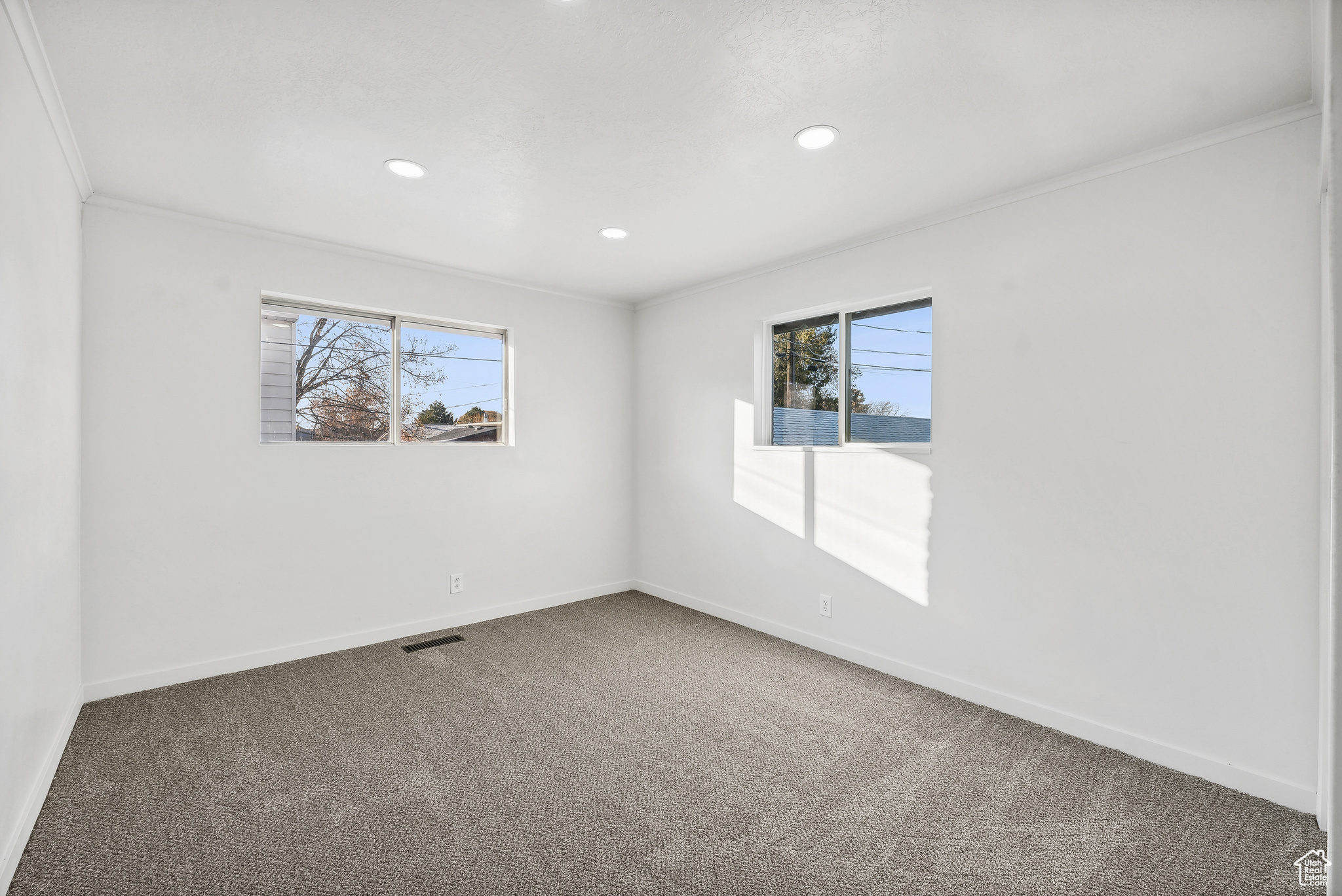 Carpeted empty room featuring ornamental molding