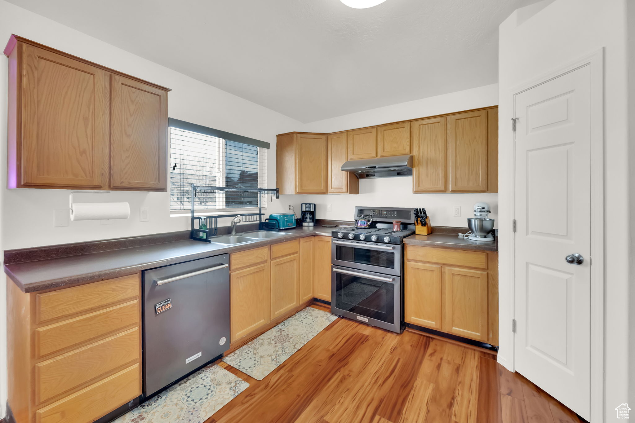 Kitchen with sink, light hardwood / wood-style floors, and appliances with stainless steel finishes