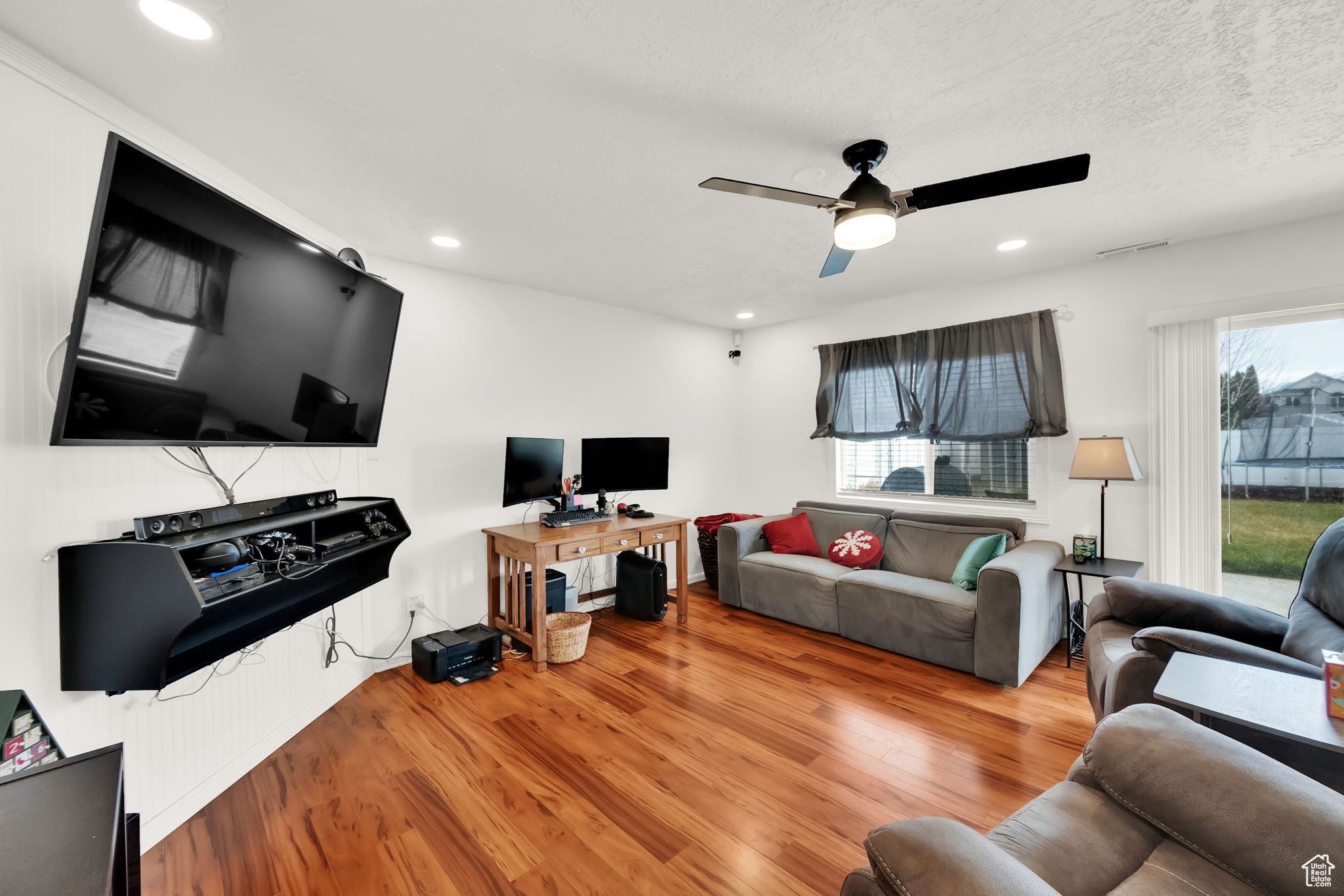 Living room with a wealth of natural light, ceiling fan, a textured ceiling, and light wood-type flooring