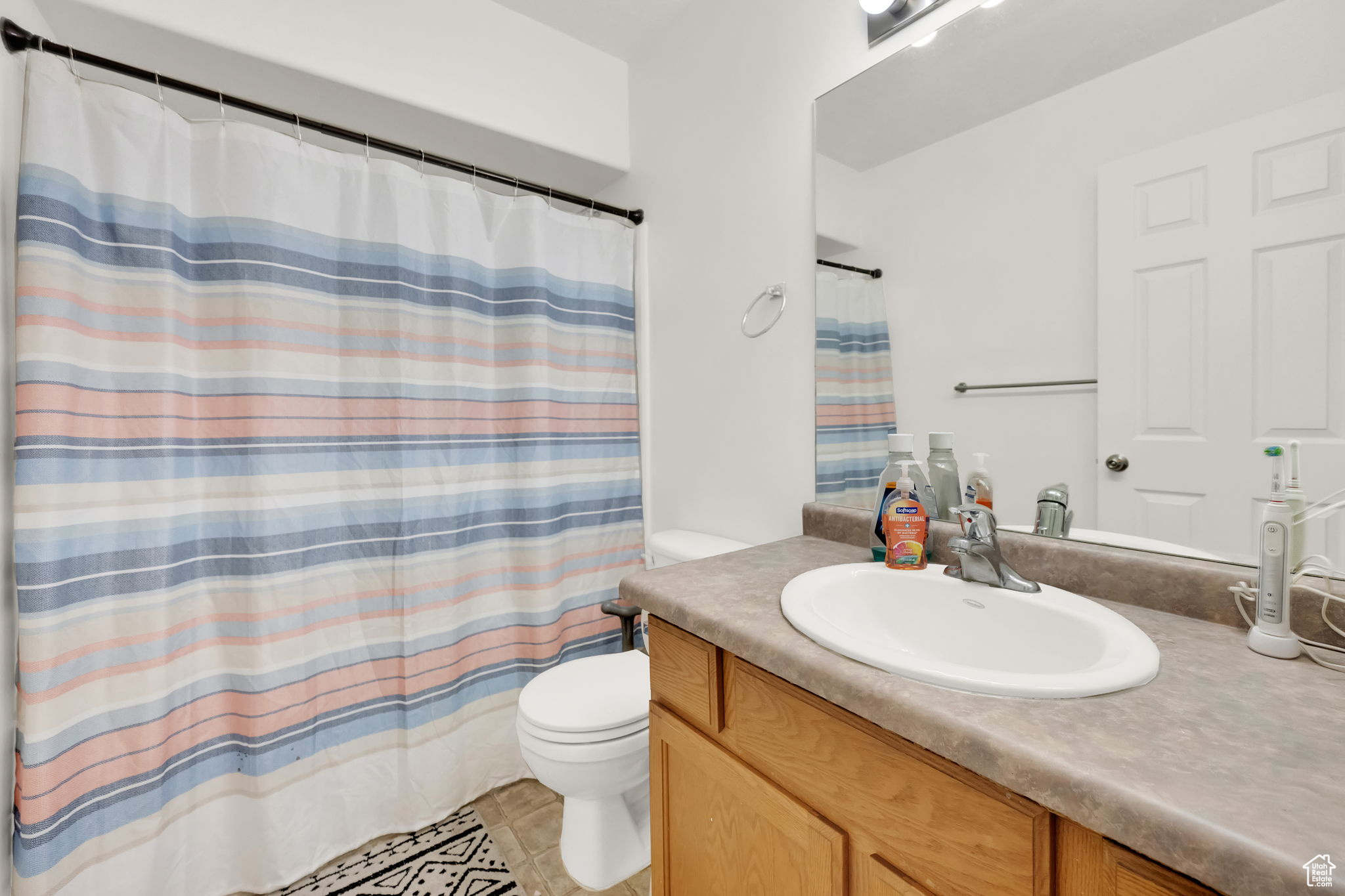 Bathroom with tile patterned floors, vanity, toilet, and a shower with curtain