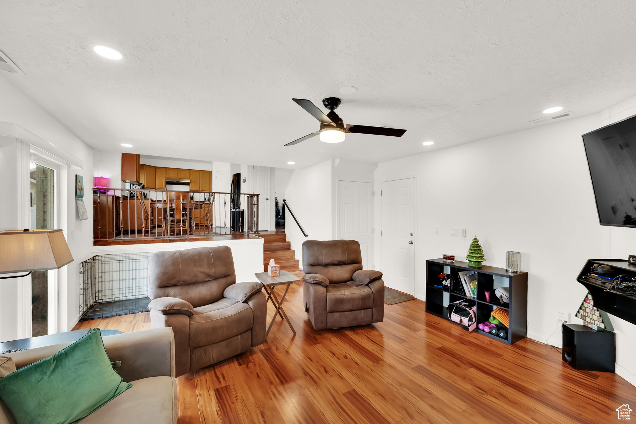 Living room featuring ceiling fan, a textured ceiling, and light hardwood / wood-style flooring