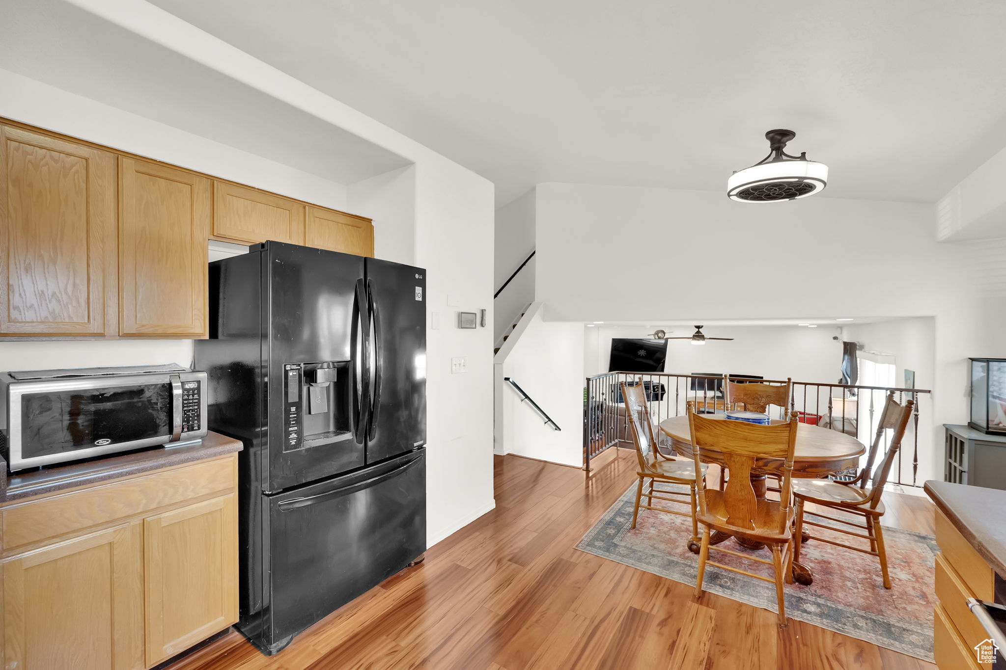 Kitchen featuring black refrigerator with ice dispenser, light hardwood / wood-style flooring, and light brown cabinets