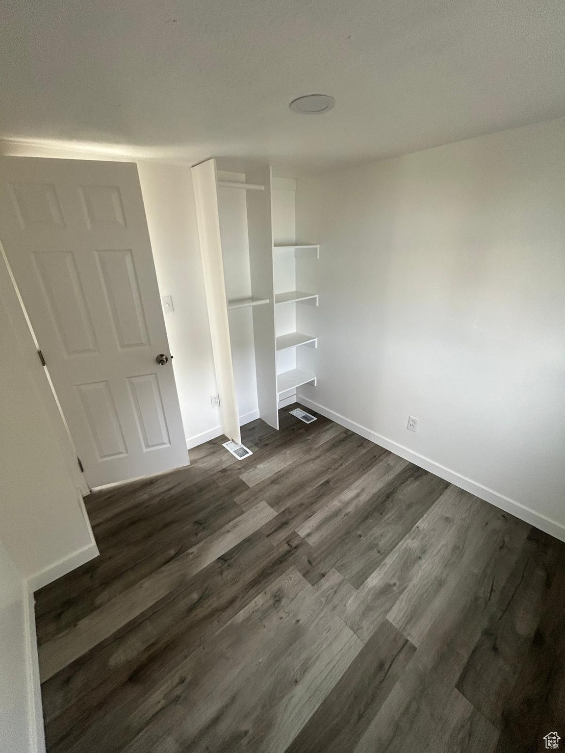 Unfurnished bedroom featuring dark hardwood / wood-style floors