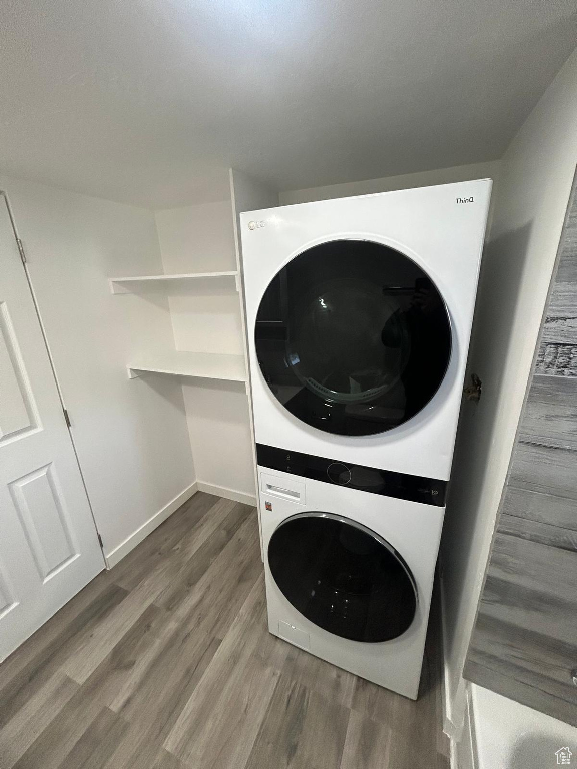 Washroom featuring hardwood / wood-style flooring and stacked washer / drying machine