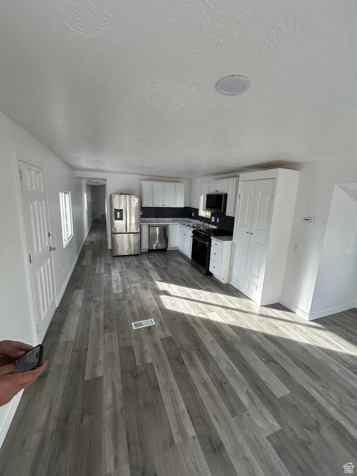 Unfurnished living room with a textured ceiling, sink, and dark hardwood / wood-style floors