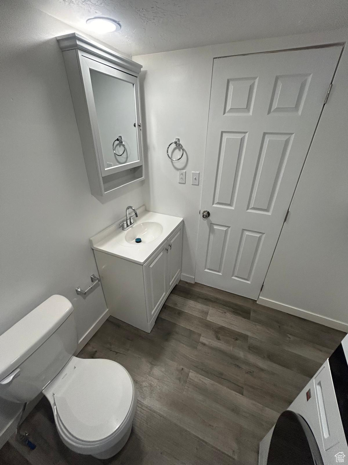 Bathroom with hardwood / wood-style floors, vanity, toilet, and a textured ceiling