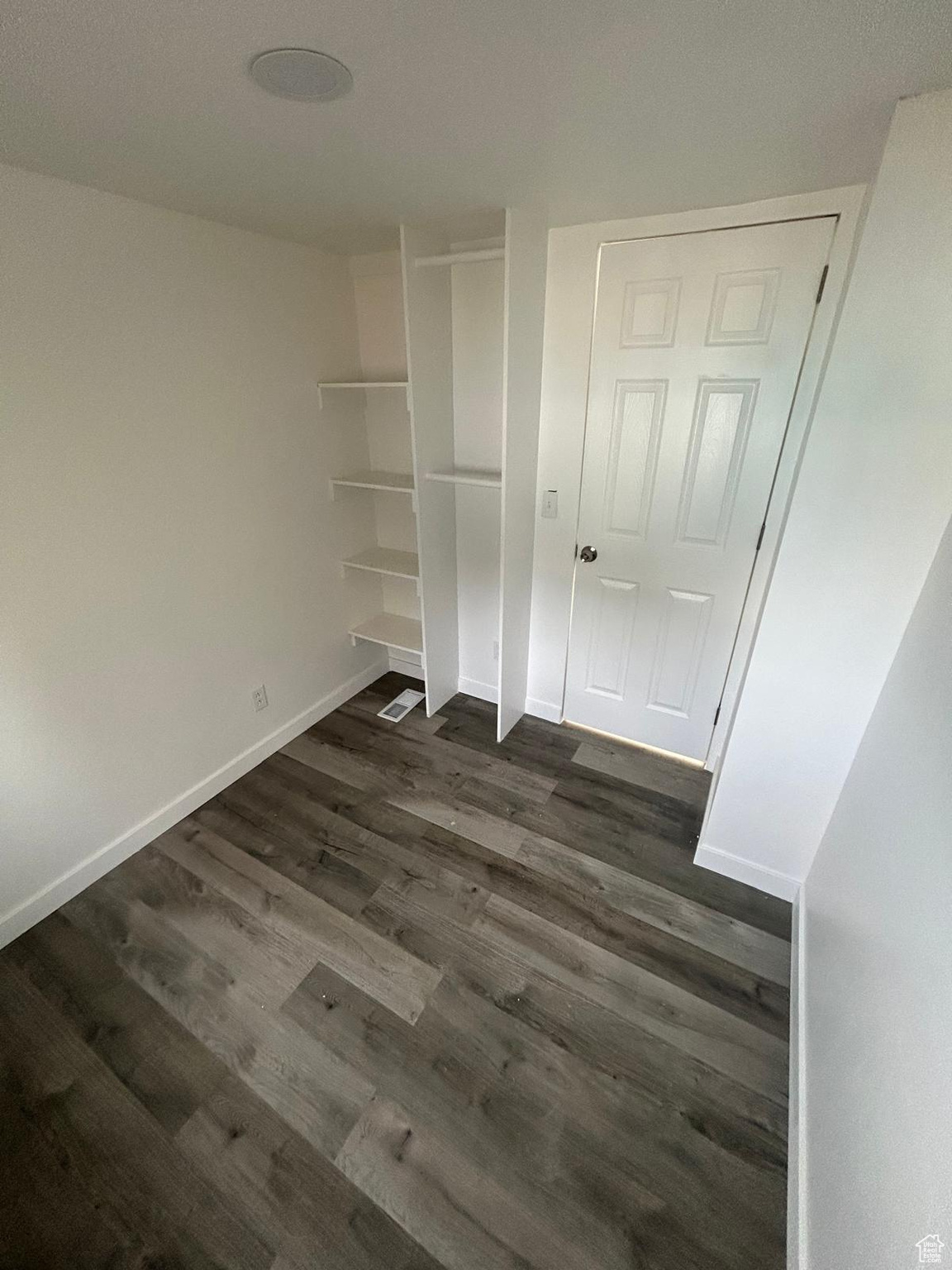 Unfurnished bedroom featuring dark hardwood / wood-style flooring