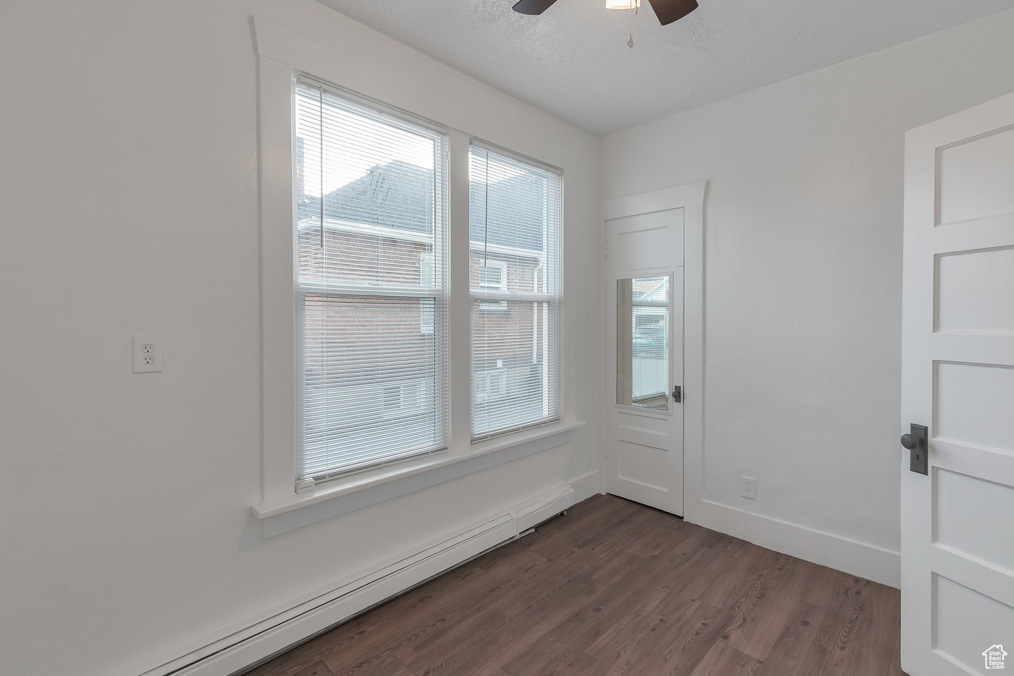 Unfurnished room featuring baseboard heating, hardwood / wood-style flooring, and ceiling fan