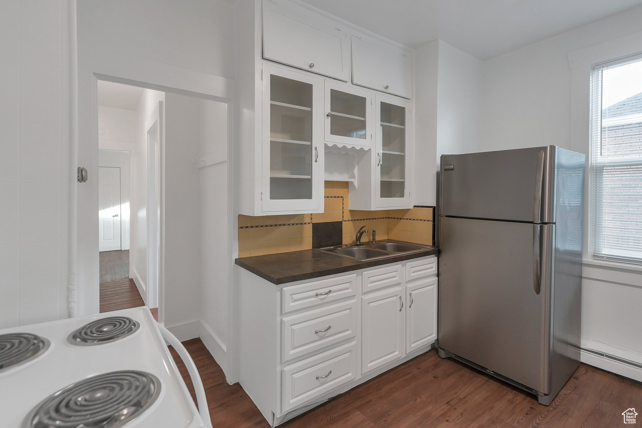 Kitchen with white cabinets, white range with electric cooktop, tasteful backsplash, sink, and stainless steel refrigerator