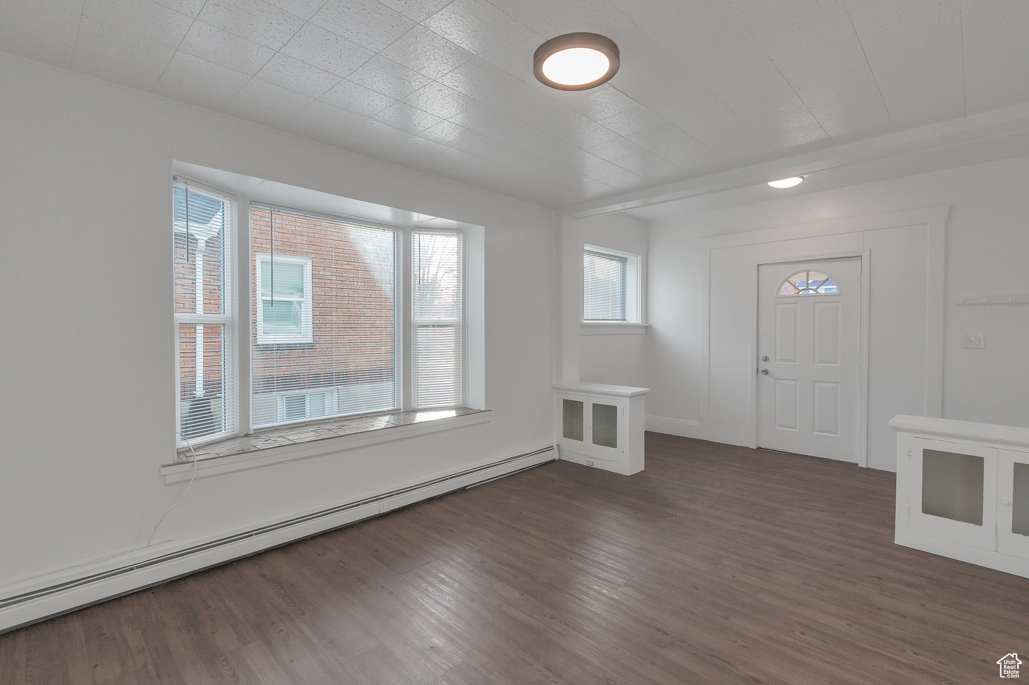 Foyer entrance featuring a baseboard heating unit and dark hardwood / wood-style flooring