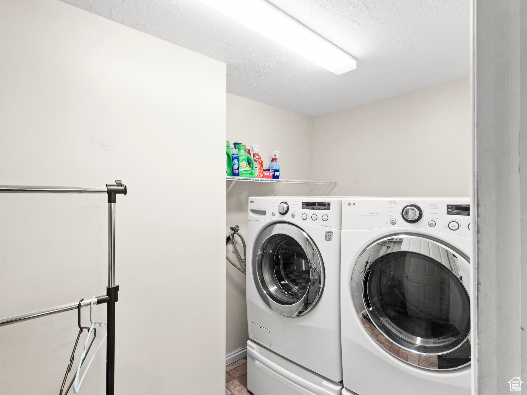 Washroom with separate washer and dryer and a textured ceiling