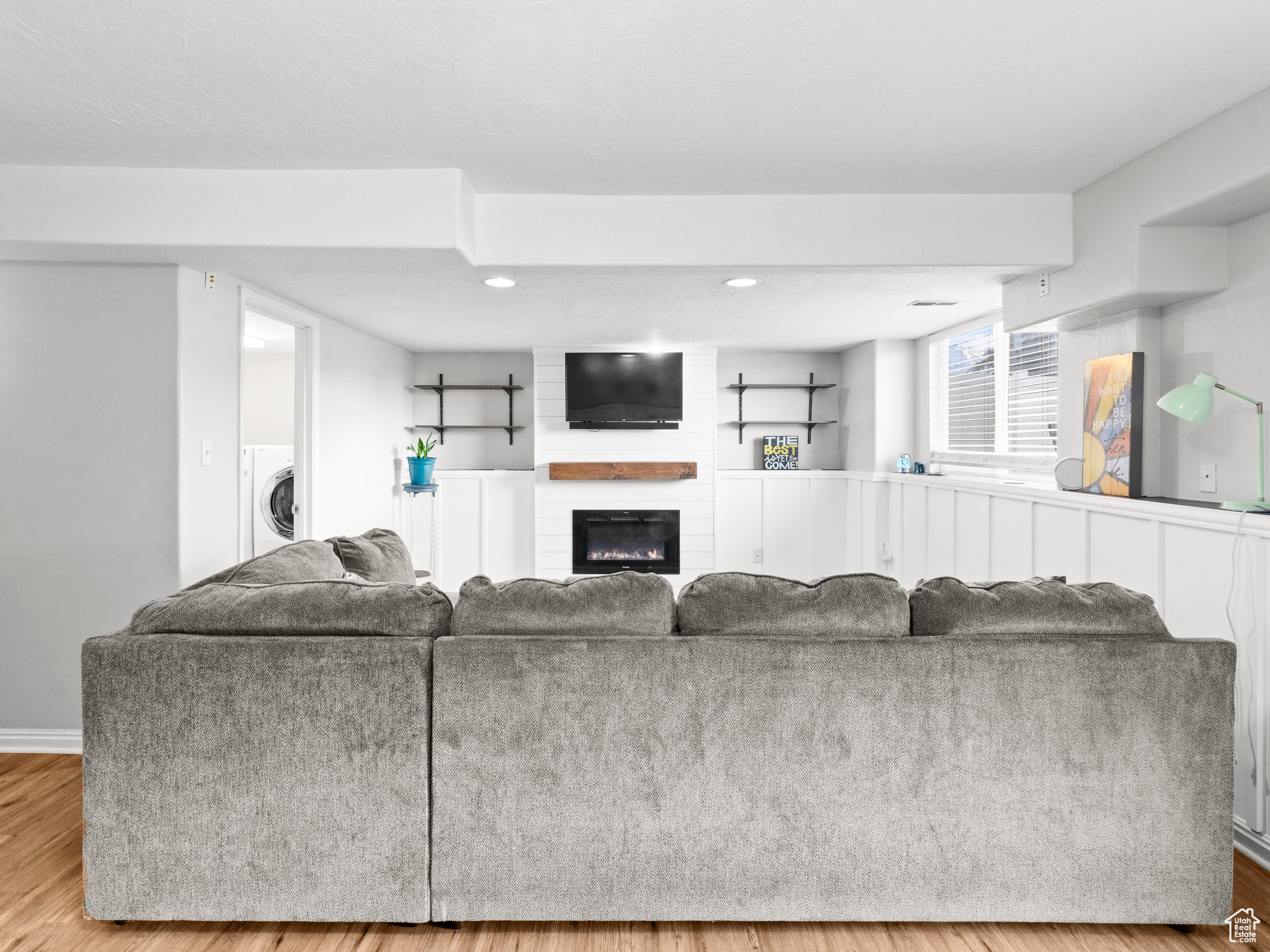 Living room with washer / dryer, a fireplace, and light hardwood / wood-style flooring