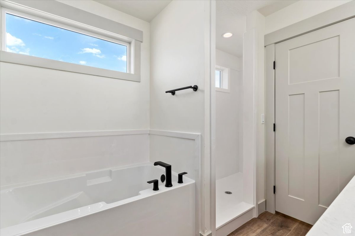 Bathroom with hardwood / wood-style floors and separate shower and tub