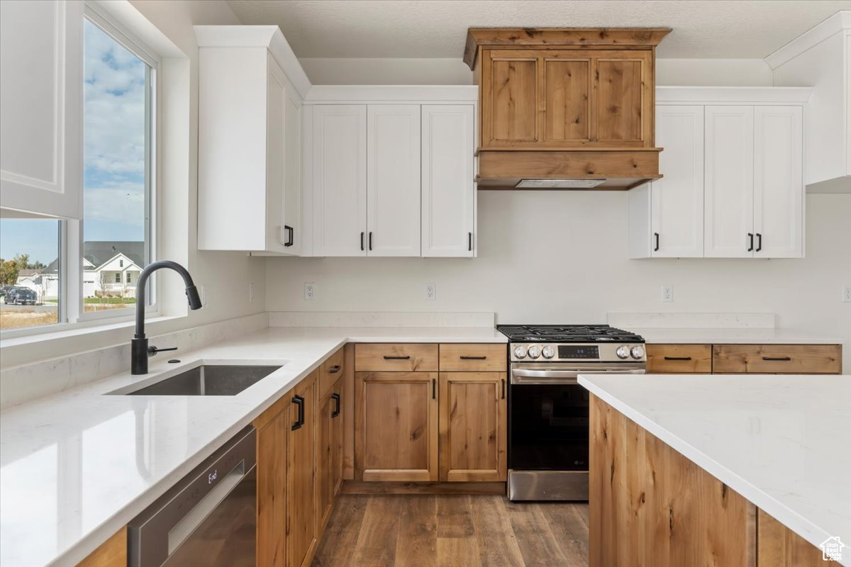 Kitchen with white cabinets, gas range, black dishwasher, and a healthy amount of sunlight