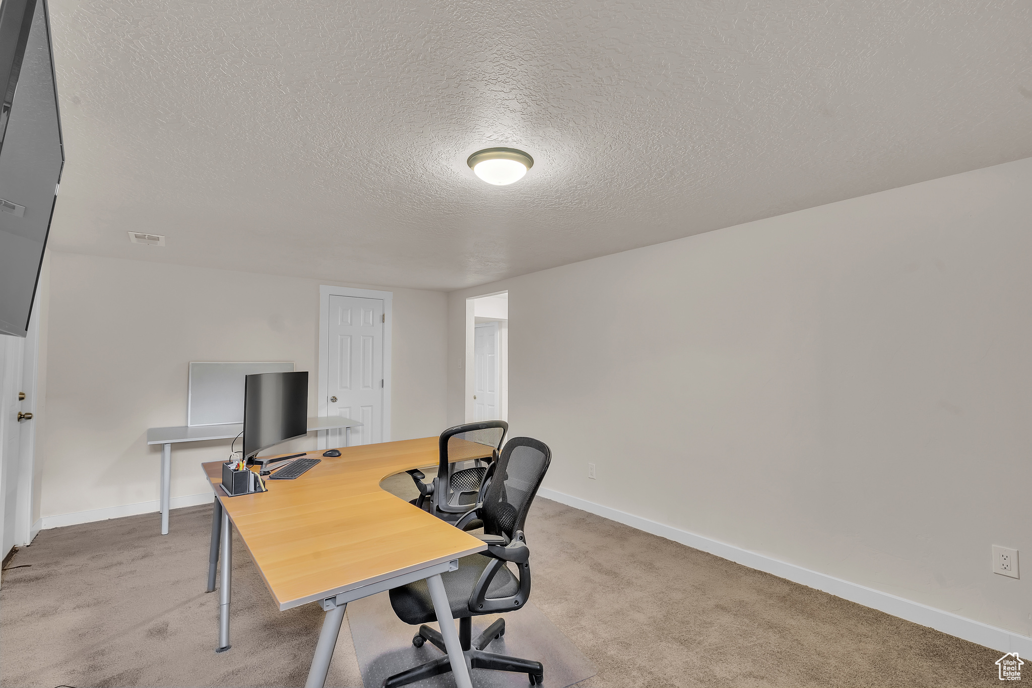 Carpeted home office featuring a textured ceiling