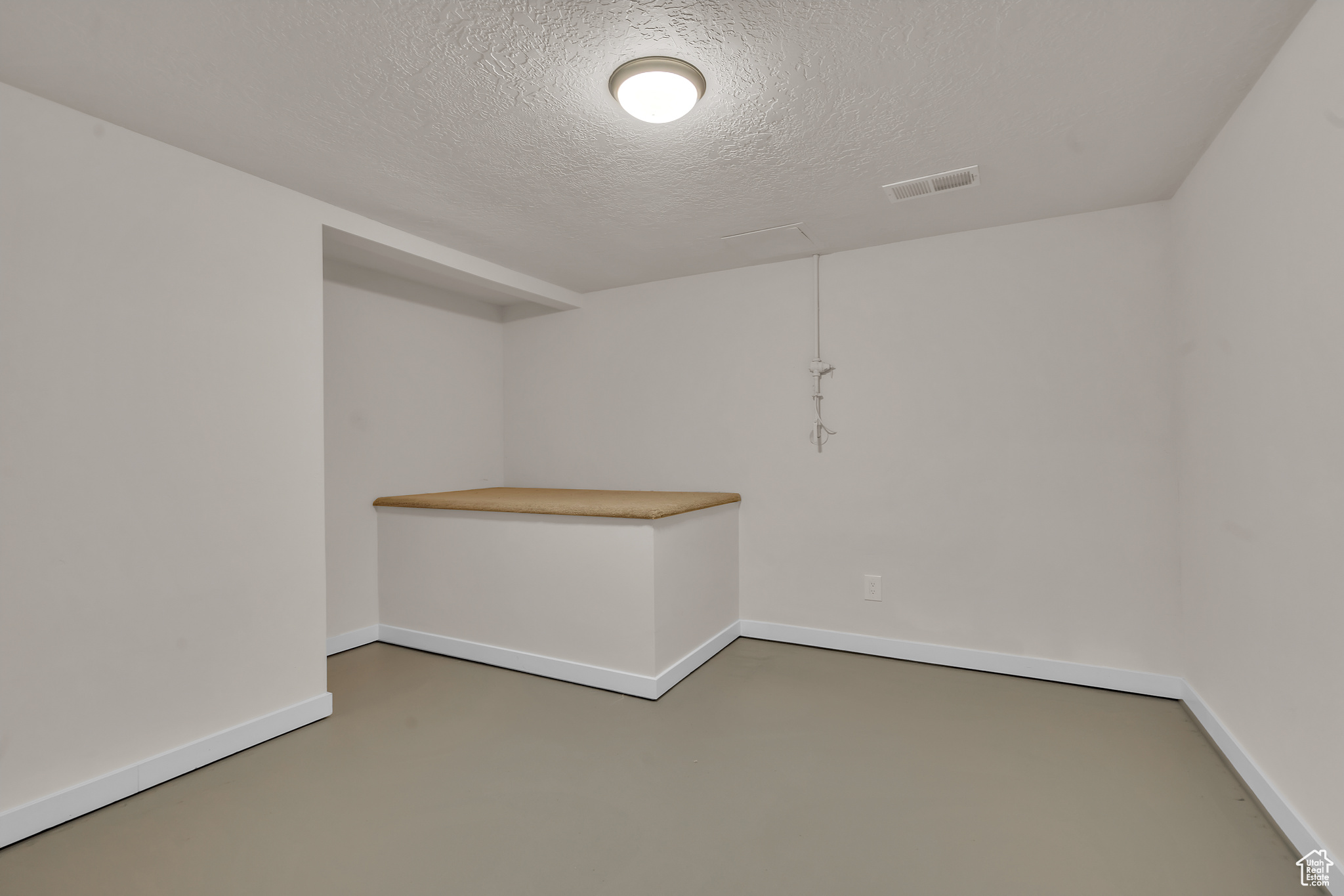 Empty room with a textured ceiling and concrete floors