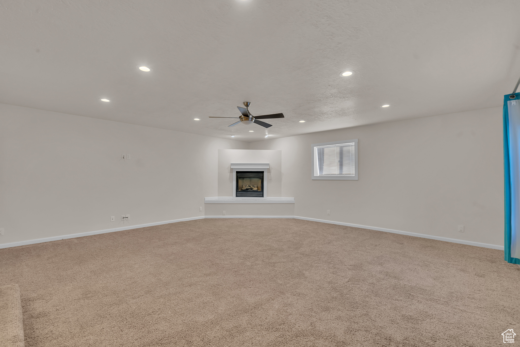 Unfurnished living room with ceiling fan and light colored carpet