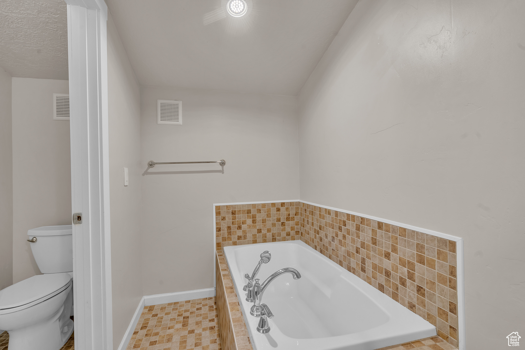 Bathroom with a relaxing tiled tub and toilet