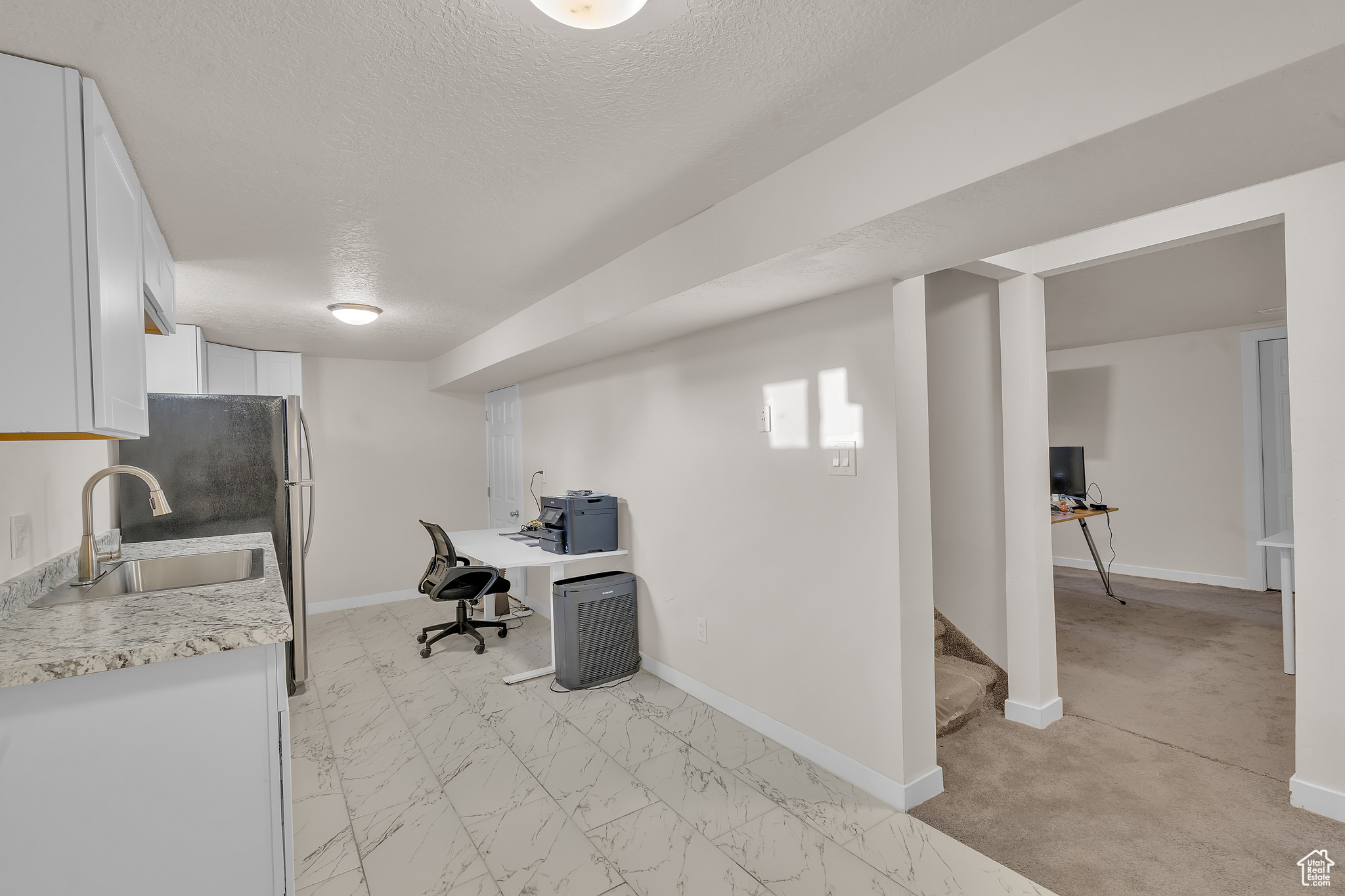 Carpeted home office with sink and a textured ceiling