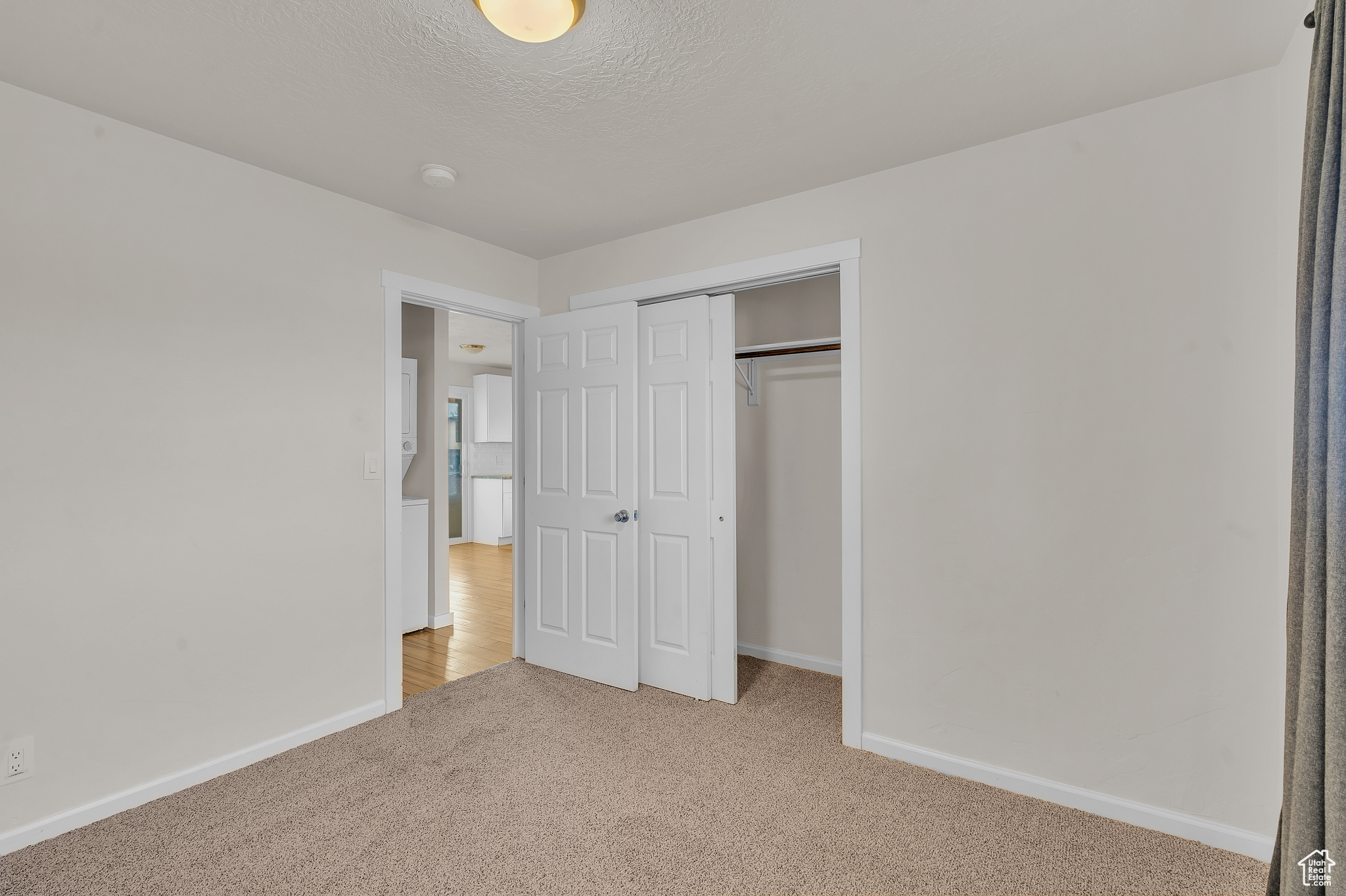 Unfurnished bedroom featuring a closet, light colored carpet, and a textured ceiling