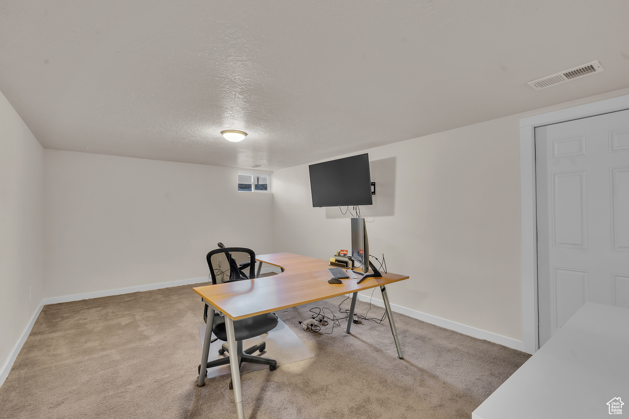 Carpeted home office with a textured ceiling