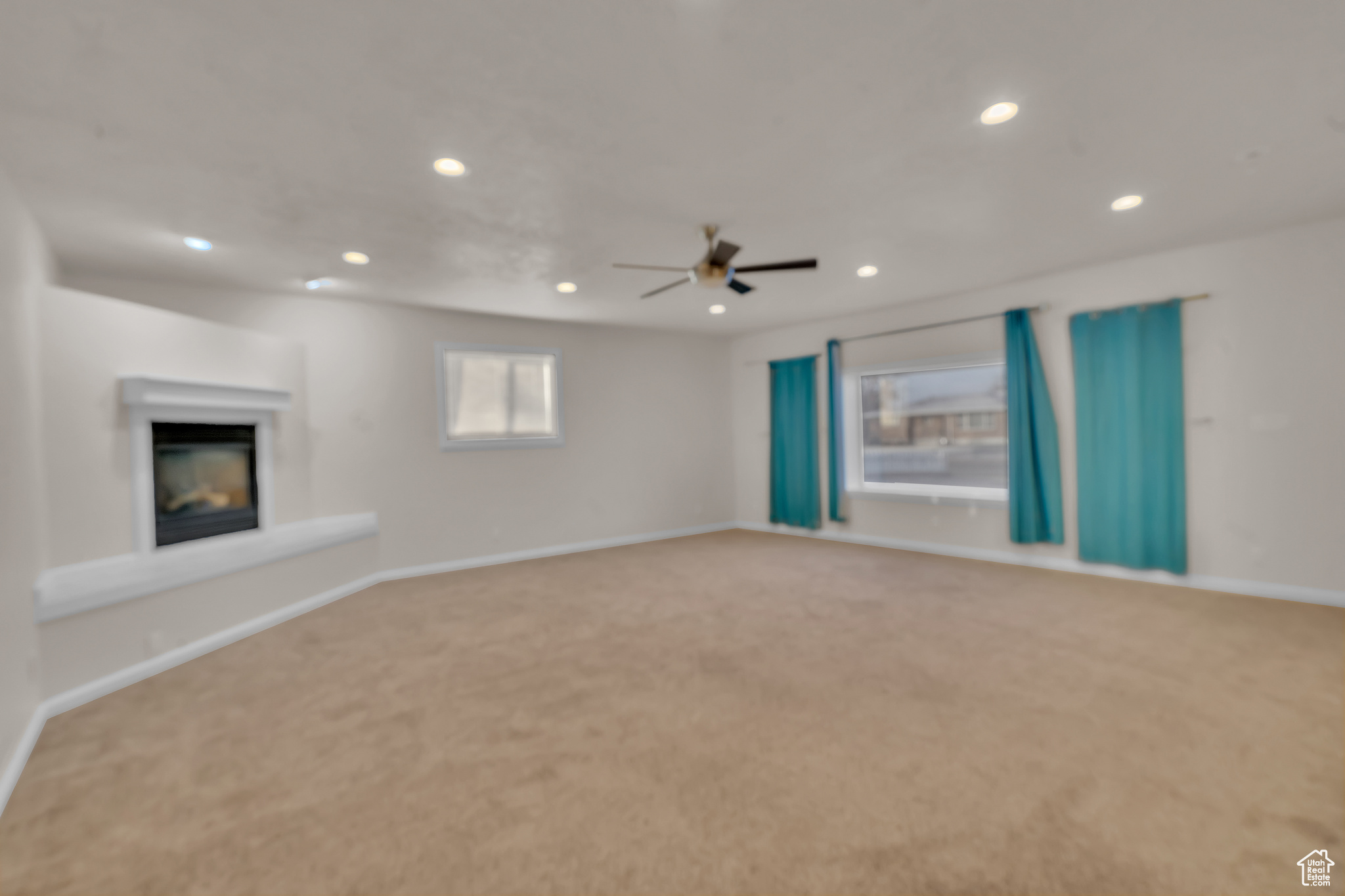 Unfurnished living room featuring ceiling fan and carpet floors