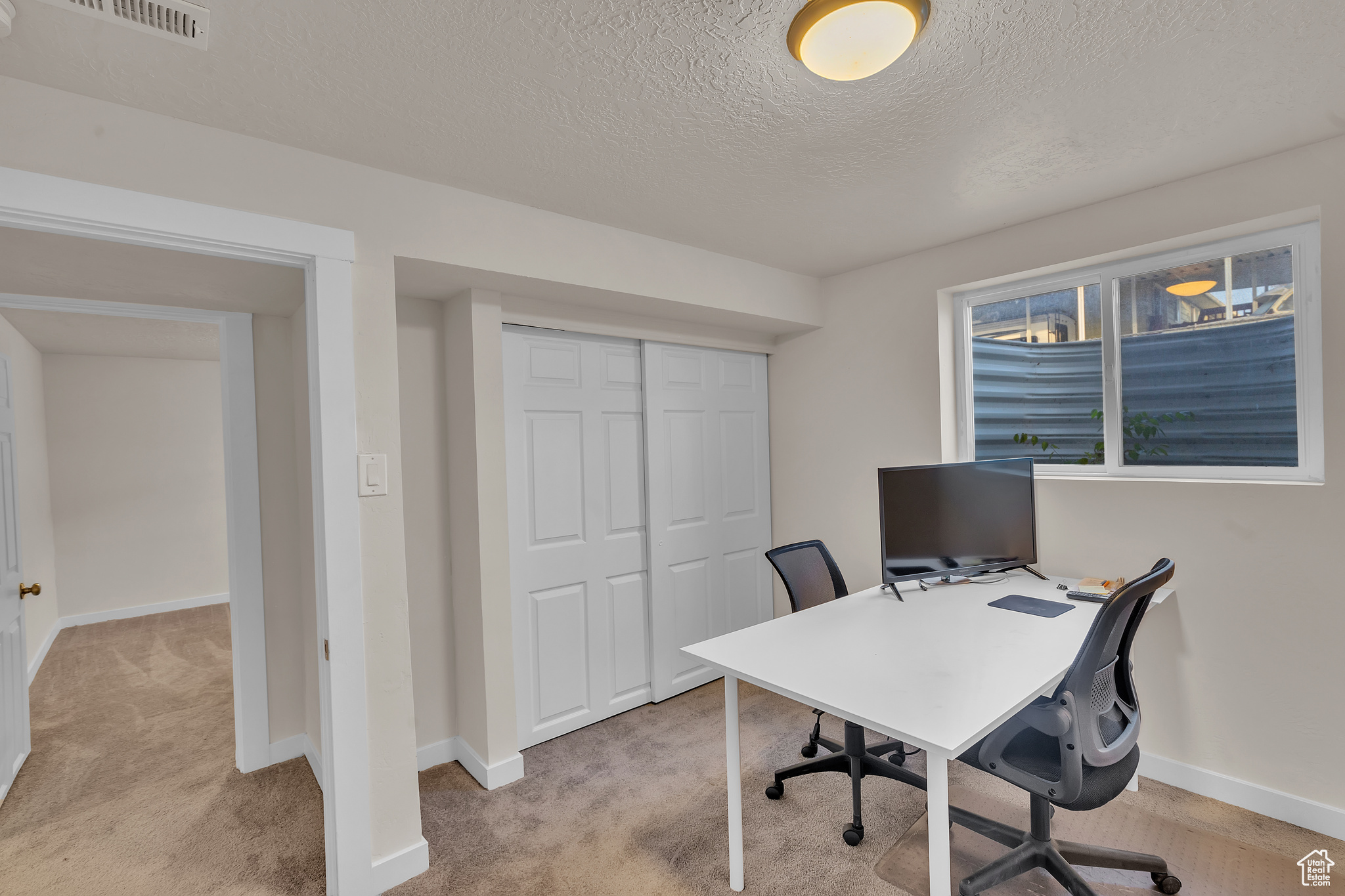 Carpeted office space featuring a textured ceiling