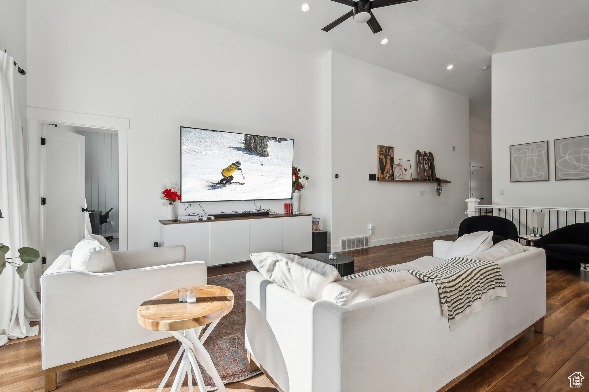 Living room with dark wood-type flooring, ceiling fan, and high vaulted ceiling