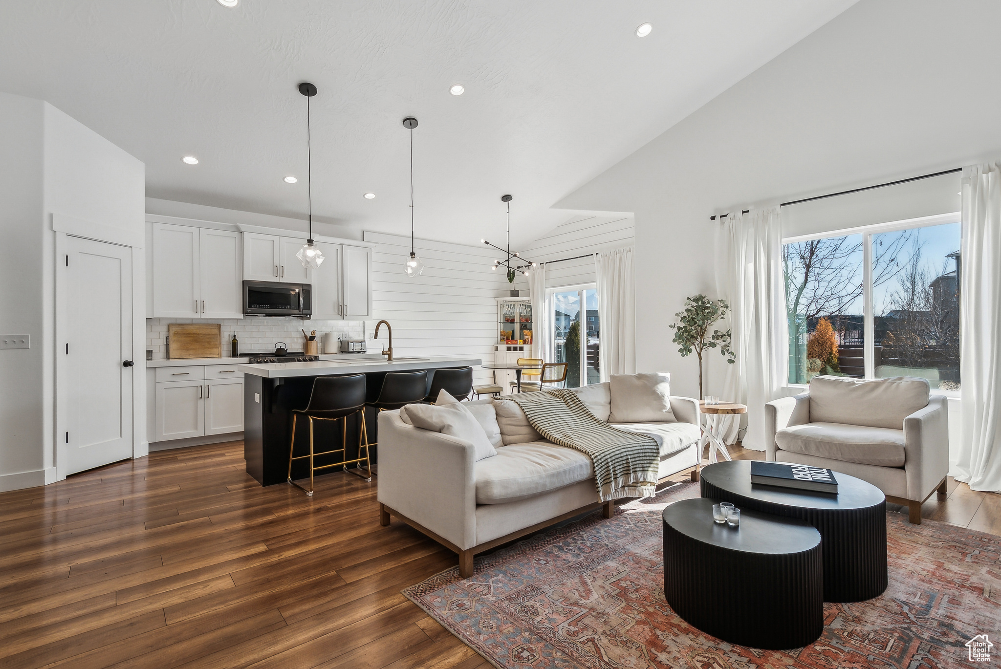 Living room with dark hardwood / wood-style floors, sink, and high vaulted ceiling