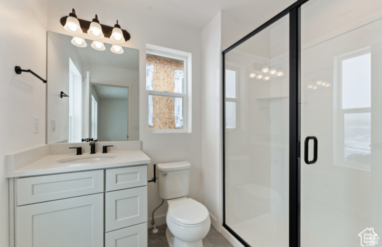 Bathroom featuring vanity, toilet, and an enclosed shower