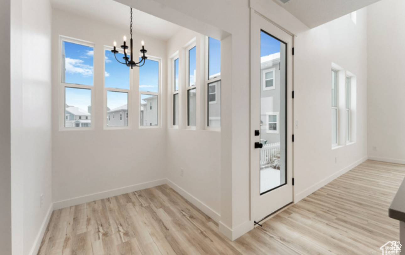 Doorway to outside featuring a notable chandelier and light wood-type flooring