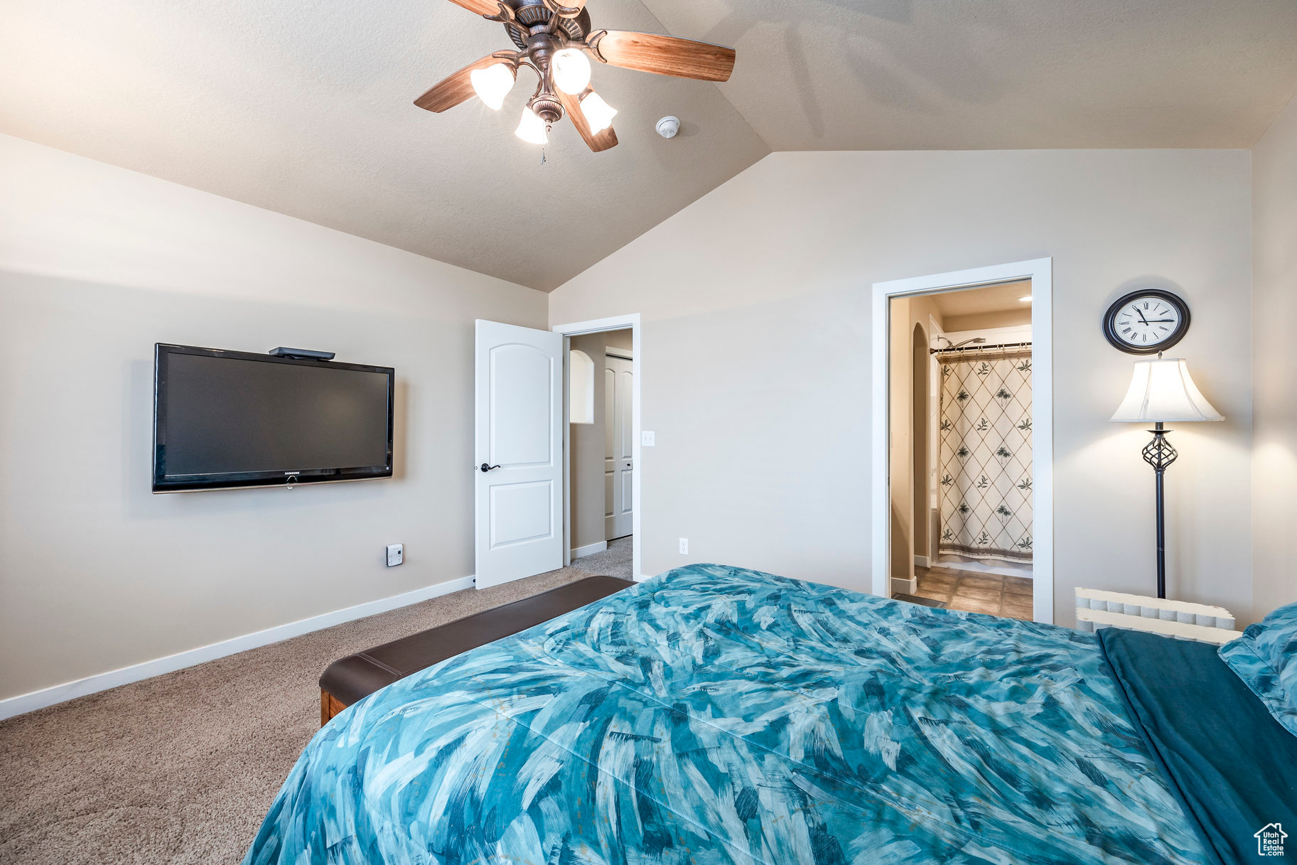 Carpeted bedroom with ensuite bath, ceiling fan, and lofted ceiling